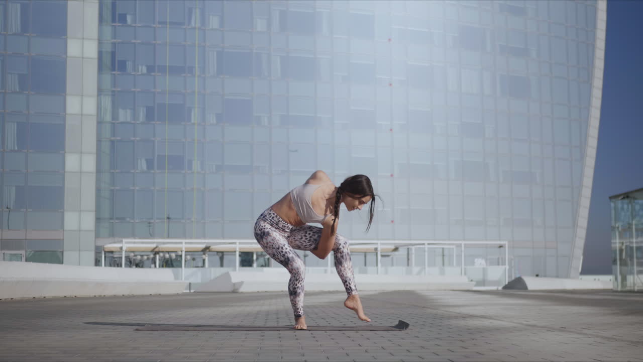 도시에서 낙원의 새 포즈를 취하는 여성. 한 다리에 균형을 잡는 요가 트레이너
