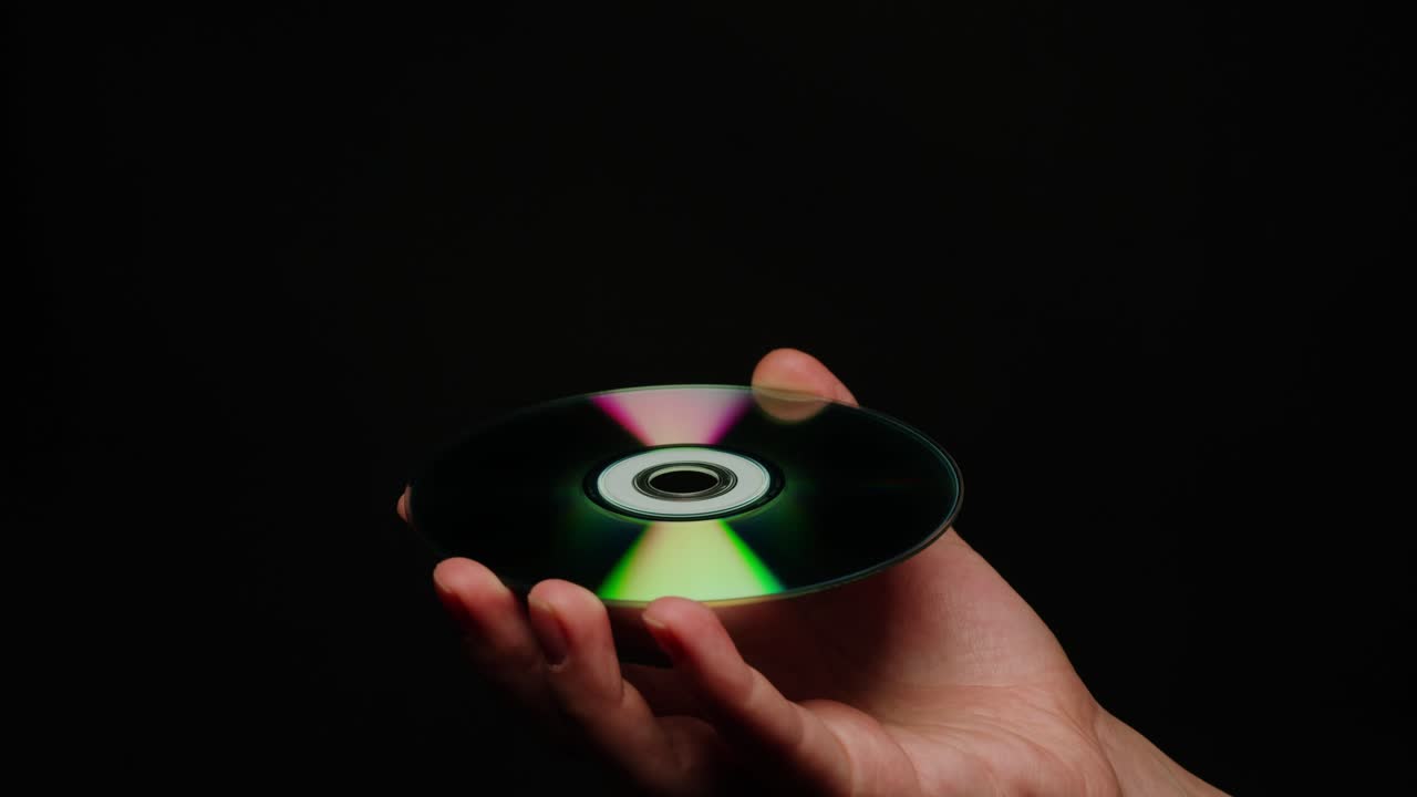 CD disk in hands on black background close-up. Old vintage disks for DVD player or computer. Music recorder, playing retro computer games.