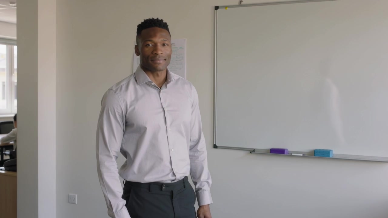Entering from left, walking man in gray shirt, pants to whiteboard in office, starting presentation