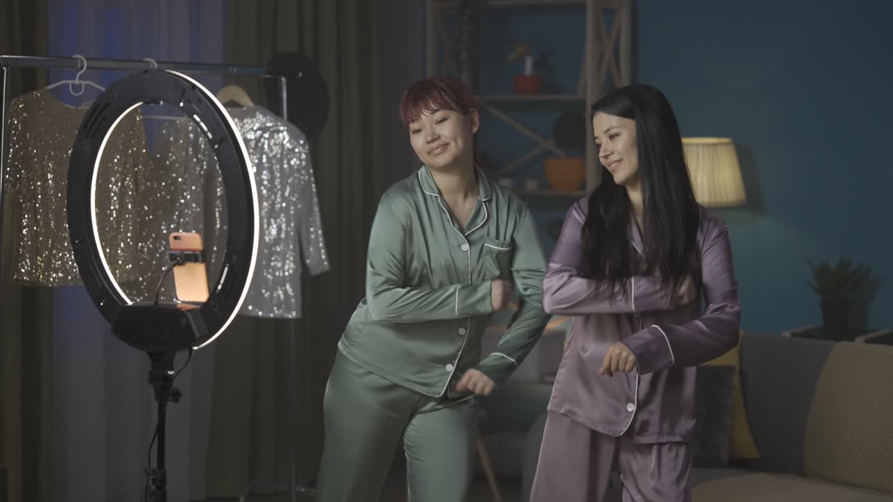 Two Women in Pajamas Dancing in Front of a Ring Light