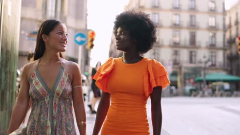 two women walking and talking on a city street