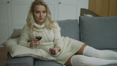 mujer sonriente con vino y control remoto