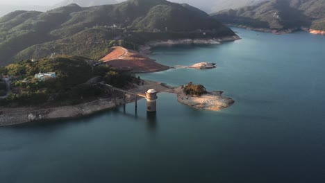 toma aérea giratoria de un depósito creado por la represa con una planta de agua a su lado para las aldeas cercanas