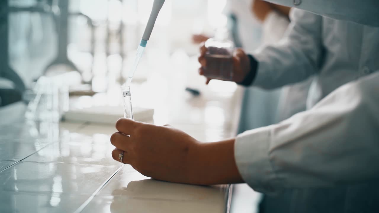 Scientists or Students Working with Pipette and Test Tube in Laboratory