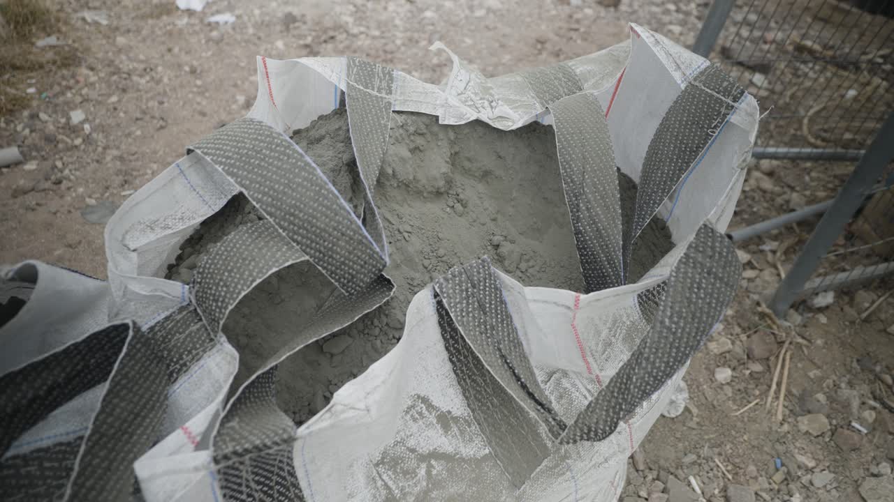 Circling Close up of a large industrial bag filled with dry cement powder at an outdoor construction site used for mixing concrete or mortar