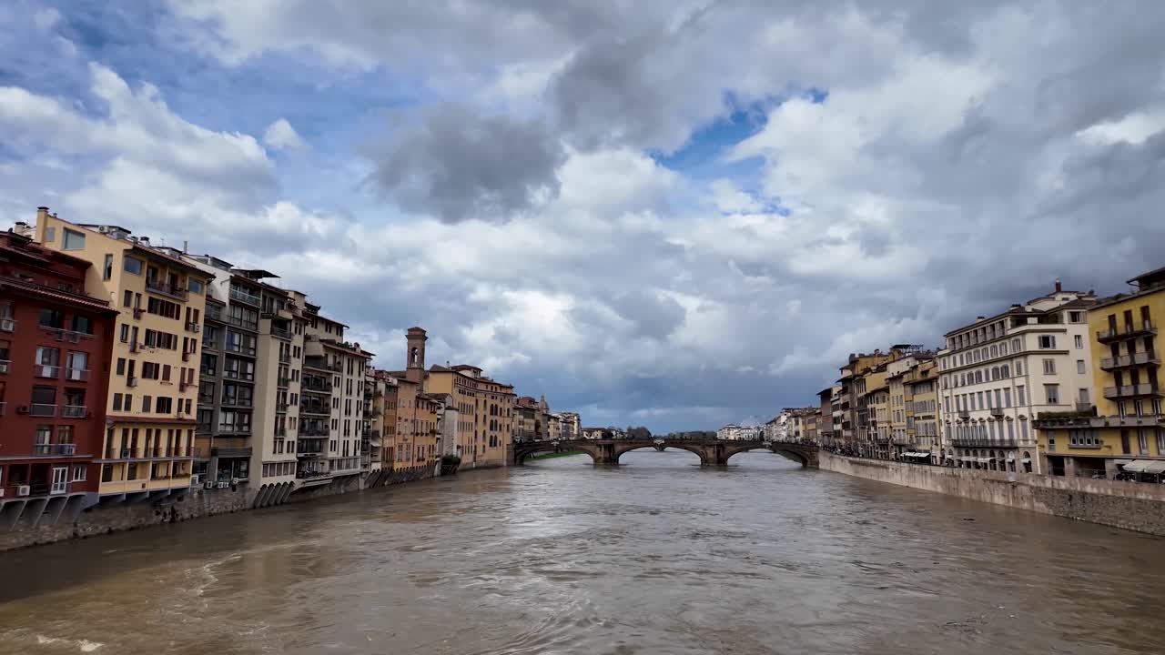 Vista panoramica al rallentatore del fiume Arno dal Ponte Vecchio a Firenze, Toscana. Le acque che scorrono e le facciate storiche incorniciano il cuore della città rinascimentale.