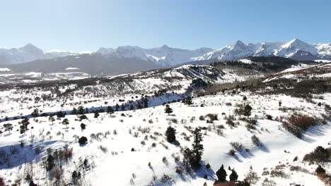 aerial cinematic drone mid winter of san juan mountain range ridgway telluride 14er stunning ranching farm land of colorado early morning mid winter blue sky pan forward up movement