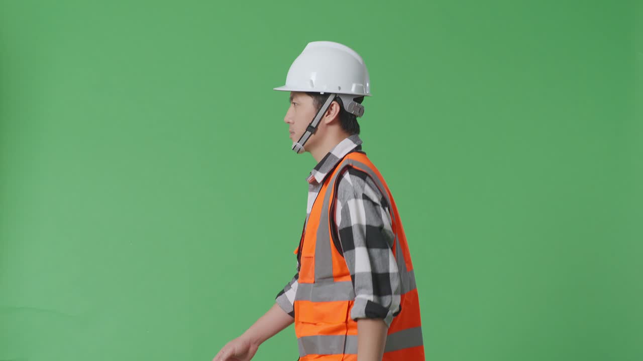 안전 헬을 입고 녹색 화면 배경 스튜디오에서 고 있는 아시아 남성 엔지니어의 측면 시각