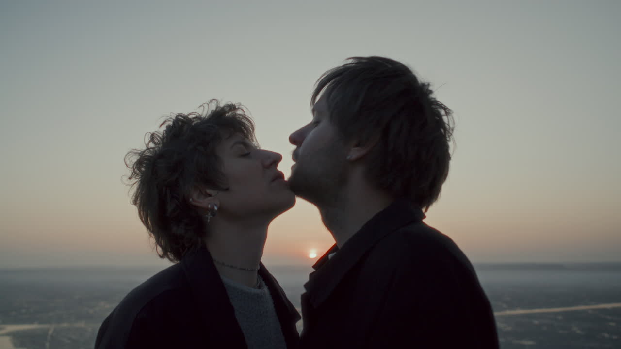 Affectionate Couple Rubbing Chins and Kissing Outdoors at Sunset