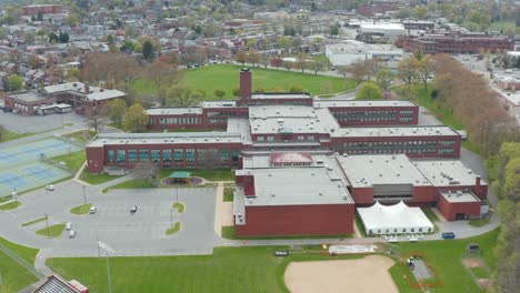 establishing orbit shot of large usa school building and athletic grounds and baseball field