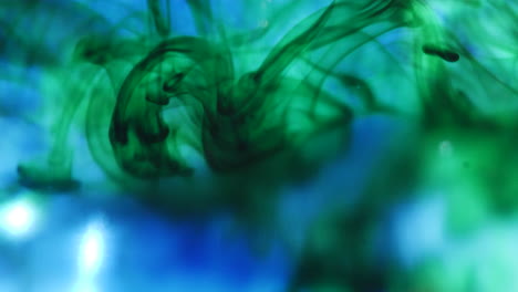Macro-shot-of-green-ink-drops-as-it-spreads-out-slowly-underwater-and-creates-smokey-abstract-shapes-in-the-background
