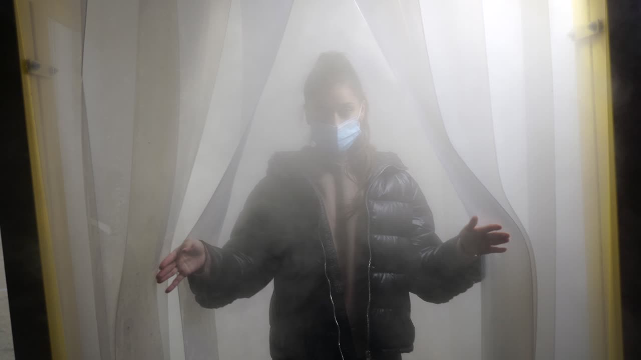 안개 가득 찬 문 앞 에 마스크 를 착용 한 여자