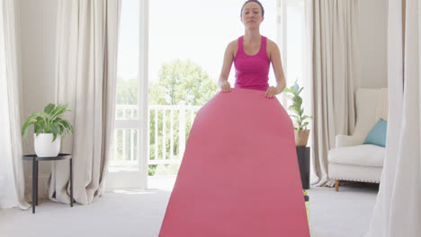 happy asian woman placing yoga mat in bedroom, in slow motion