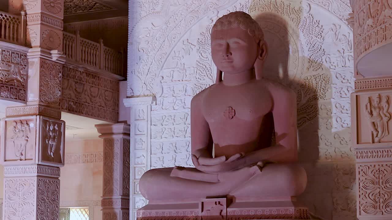estatua sagrada de piedra roja aislada de dios jainista en meditación desde diferentes ángulos el video se tomó en shri digamber jain gyanoday tirth kshetra, nareli jain mandir, ajmer, rajasthan, india