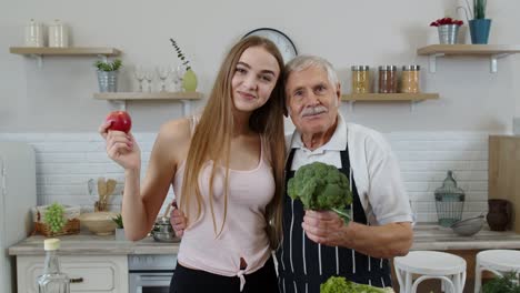 senior grandfather with granddaughter recommending eating raw vegetable food. vegetable diet