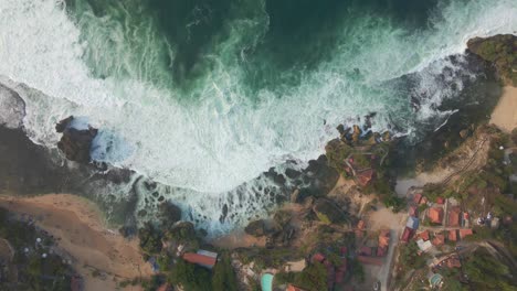 overhead drone shot of ocean waves rolling onto tropical shoreline