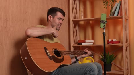 hombre tocando la guitarra acústica en casa