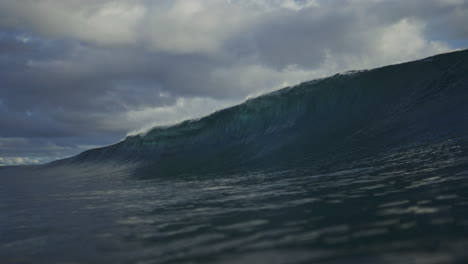 Wave-glistens-as-it-grows-and-face-breaks-spraying-mist-over-top-curling-into-barrel,-slow-motion