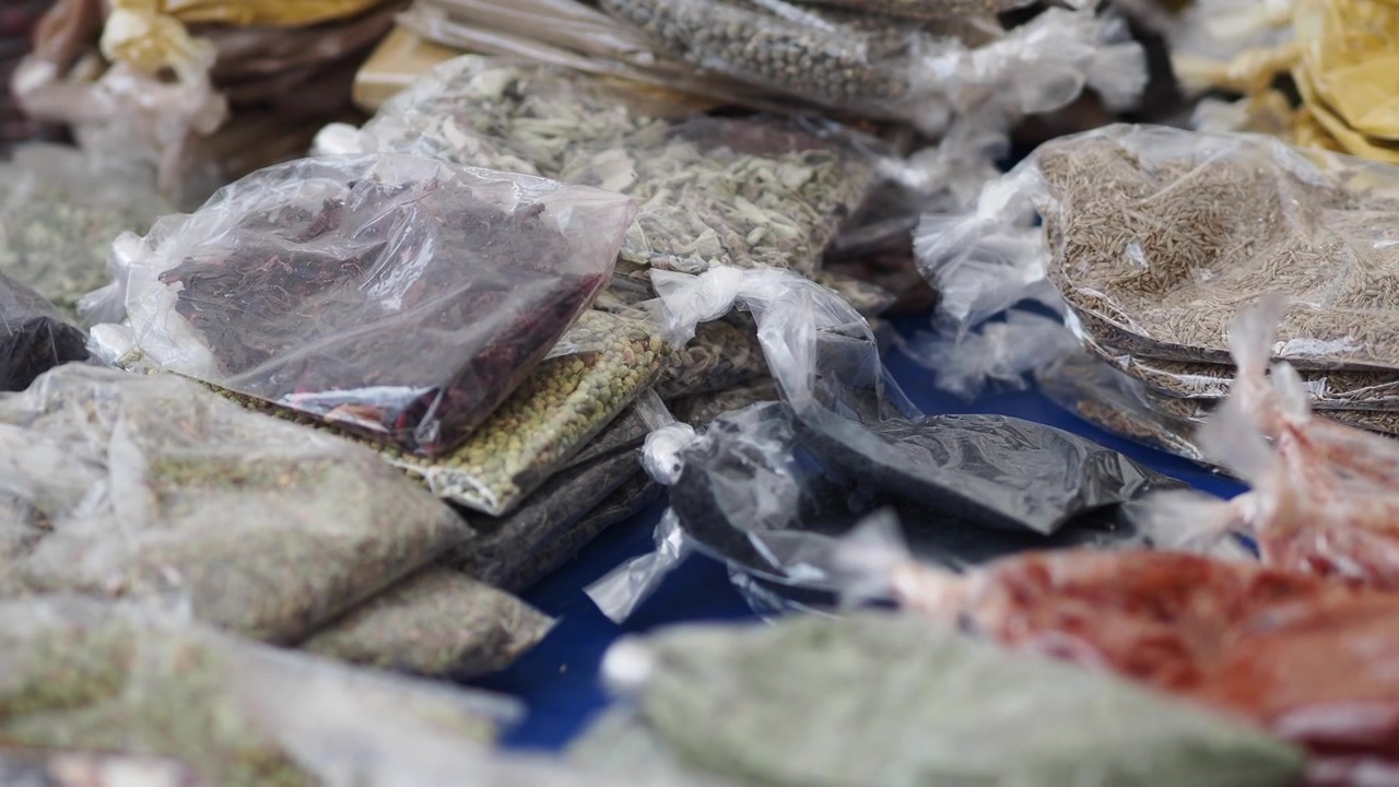 Mano che seleziona spezie confezionate in una bancarella del mercato locale