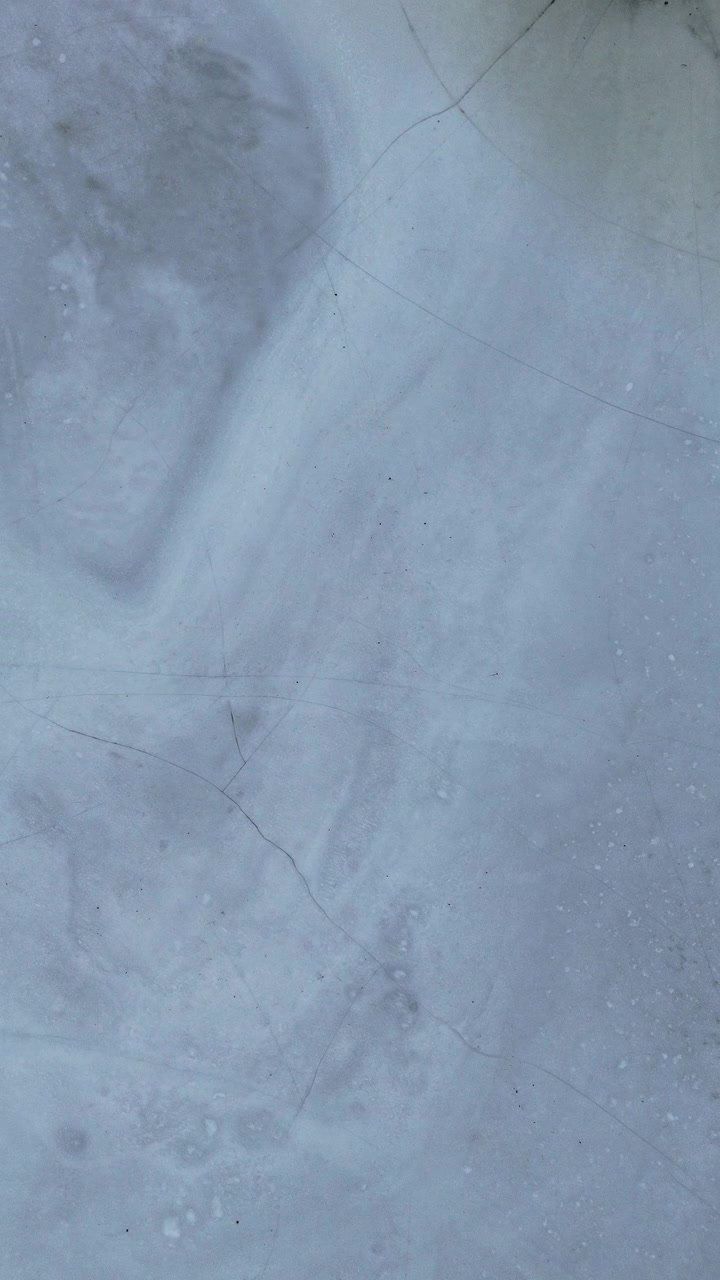Close-up view of intricate ice patterns and cracks on a frozen lake. Ideal for winter-themed projects or environmental documentaries.