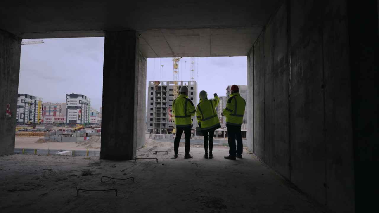 tres personas con cascos y uniformes están viendo el sitio de construcción el equipo de ingeniería está inspeccionando