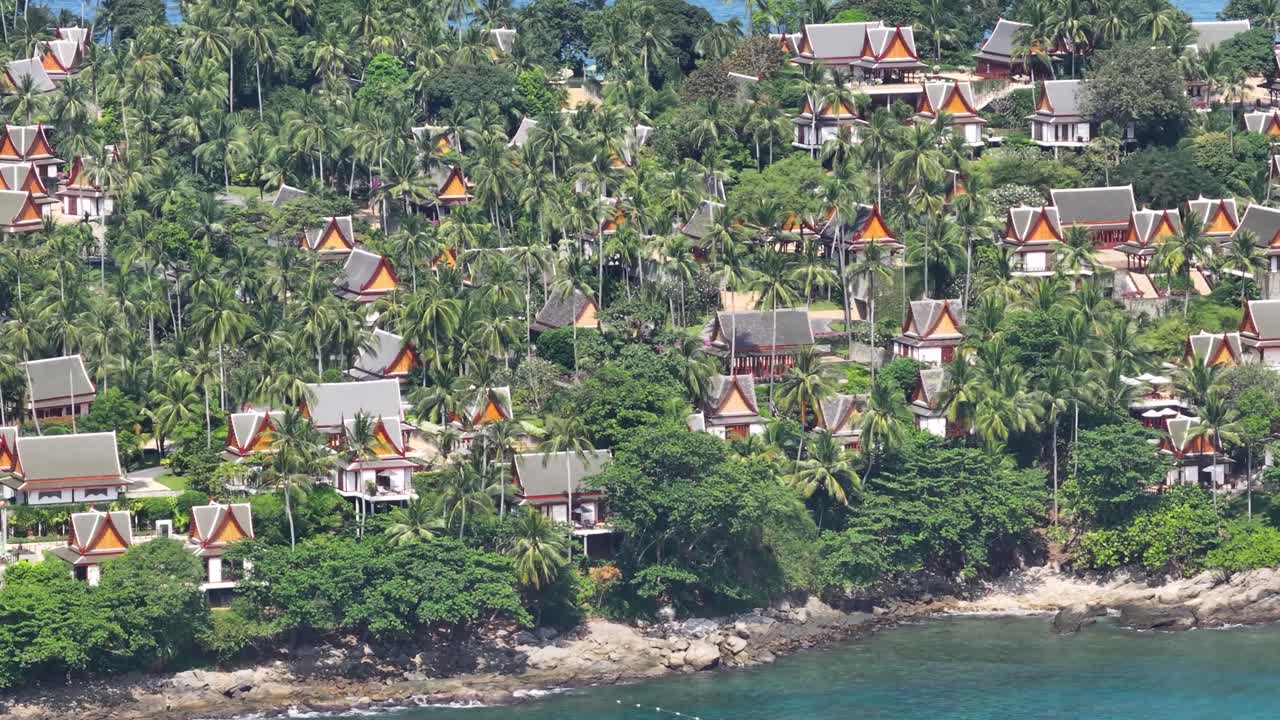 Aerial close up colourful villas and small temples in exotic palm forest. Luxury resort in Phuket.