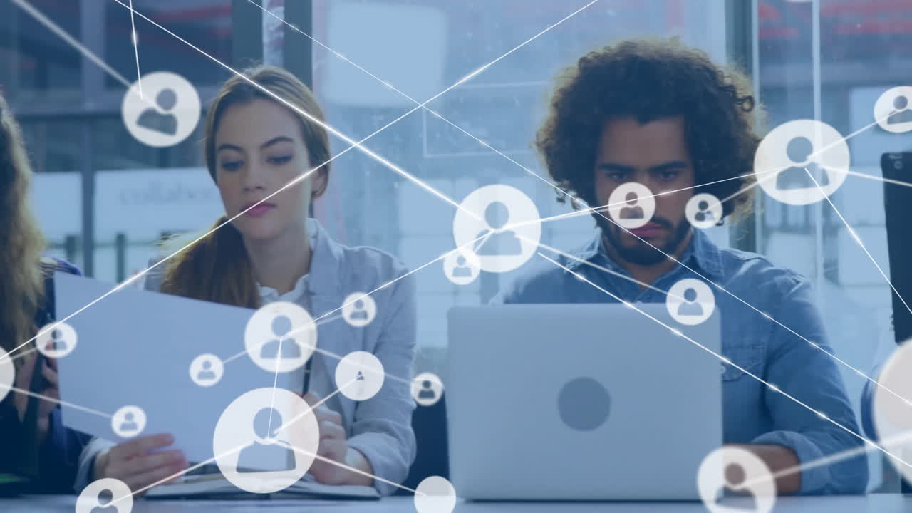 Animation of network of connections with icons over diverse colleagues using laptops in office