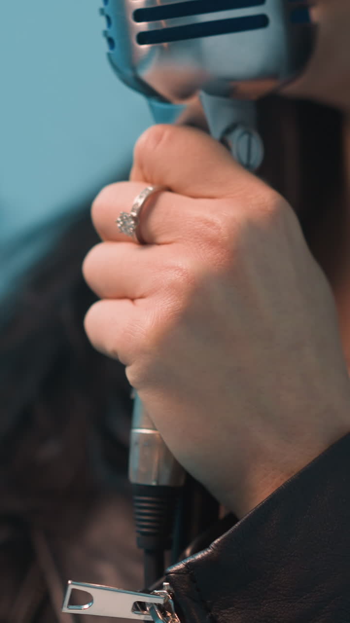 cantante femenina apasionada con un sombrero negro y una chaqueta de cuero, sosteniendo un micrófono vintage con una mano y moviendo la otra expresivamente, actuando contra un fondo blanco