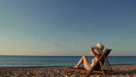woman in a straw hat relaxing on a beach chair by the ocean