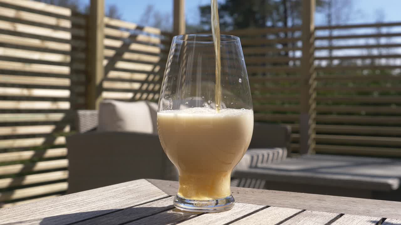 여름 에 나무 테이블 위 에 있는 잔 에 어두운 아이파 맥주 를  ⁇ 우는 것