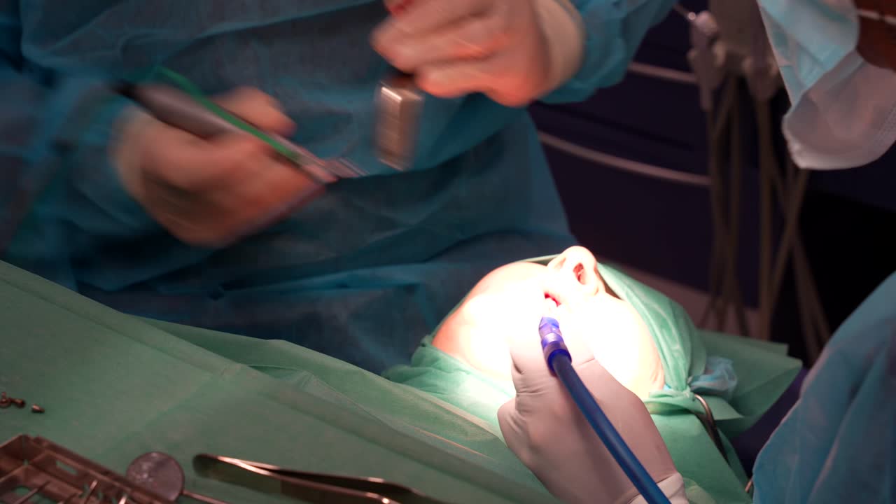 primer plano de un asistente que ayuda al dentista con un eyector de saliva durante un procedimiento dental