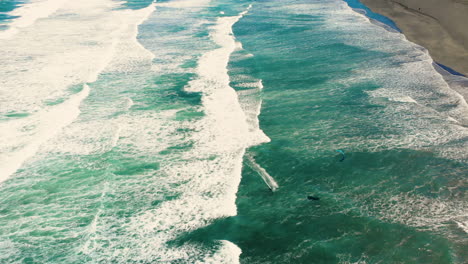 sporty guy kiteboarding at scenic waves at piha beach in new zealand