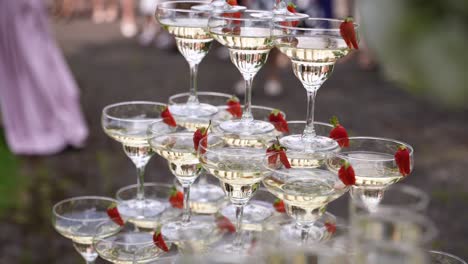the shot of the champagne glass pyramid with strawberries in glasses during the wedding
