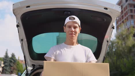 moving and delivery of manufactured goods. an employee holds a box in his hands and stands next to a car filled with parcels. express delivery