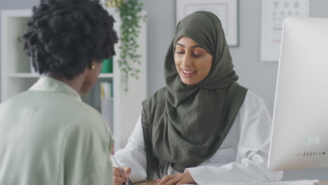 Female-Doctor-Or-Consultant-Wearing-Headscarf-Having-Meeting-With-Female-Patient-To-Discuss-Scans