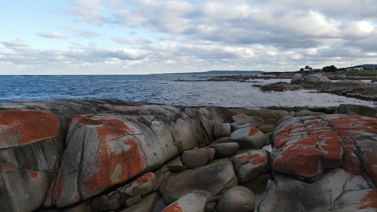 Droneoptagelse af de røde klipper ved Bay of Fires ud mod oceanet, Tasmaniens natur, SLOW MOTION 60fps.