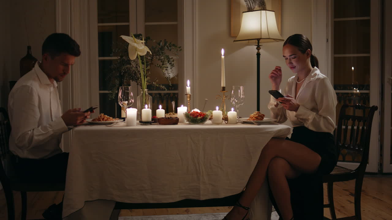 스마트폰을 사용하는 젊은 부부는 로맨틱한 저녁. 남녀는 서로를 무시합니다.