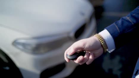 hombre de negocios usando llave de coche y teléfono inteligente cerca de un coche