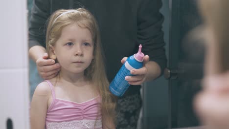 pretty-girl-and-mom-with-bottle-for-rinsing-nose-at-mirror