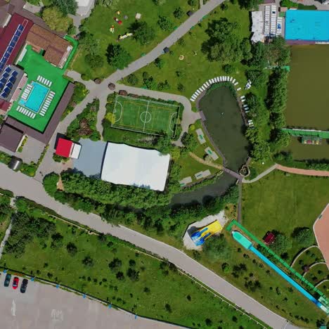 panoramic view of a modern complex. recreation area with football pitch and swimming pool near the river. resting center among green nature. top aerial view.