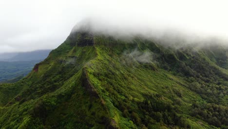 drone rising above a hawaiian mountain on east oahu flying into clouds