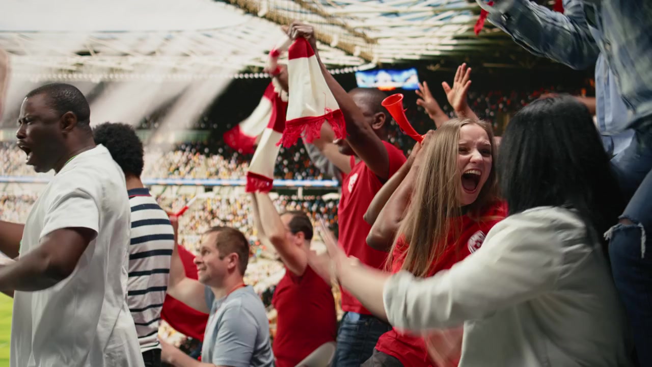 Begejstrede kvindelige fodboldfans læner sig frem og hepper fra stadionpladserne