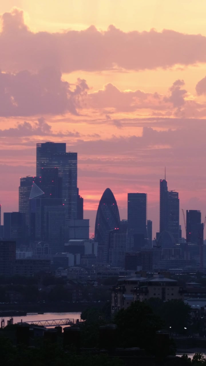 Vista verticale con teleobiettivo dello skyline di Londra con il Gherkin e 22 Bishopsgate incorniciati contro nuvole drammatiche rosa e arancioni al tramonto