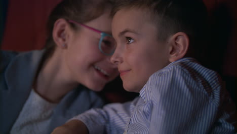 chica susurrando a chico viendo una película en el cine. entretenimiento de películas para niños