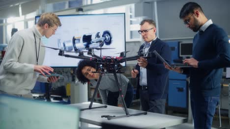 un grupo diverso de jóvenes especialistas hablan con el ingeniero jefe. profesionales usan portátiles trabajando en el diseño de drones en un brillante laboratorio moderno de alta tecnología
