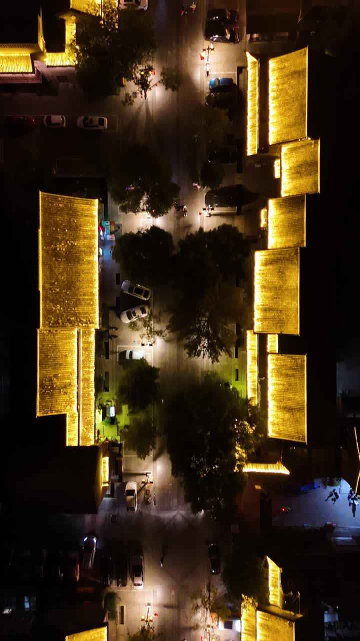 Vertical top-down aerial view of Lounan Street in Liaocheng, Shandong Province, showcasing the historic Guangyuelou Tower from the Qing Dynasty. UHD footage highlights the vibrant street life.