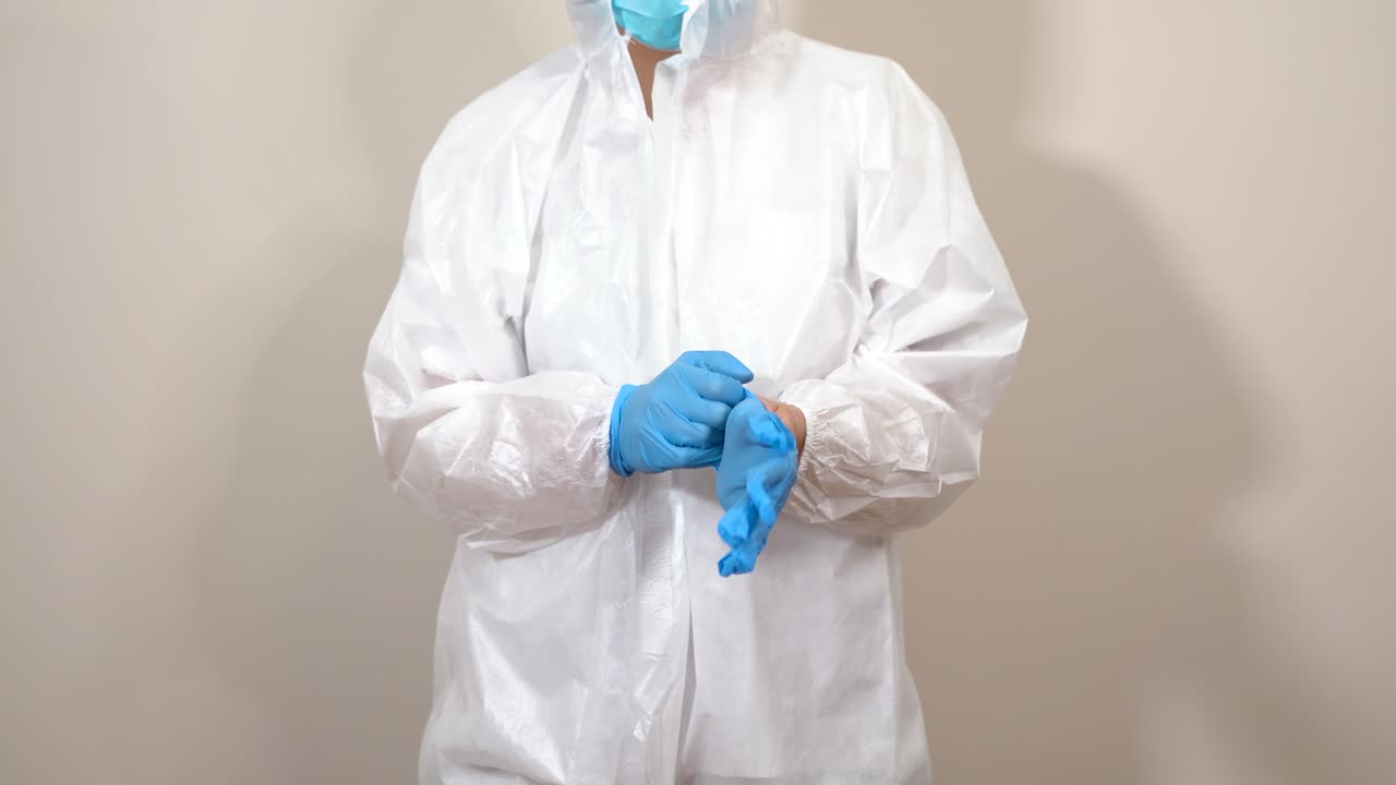 female doctor in ppe suit putting on gloves in front of the camera