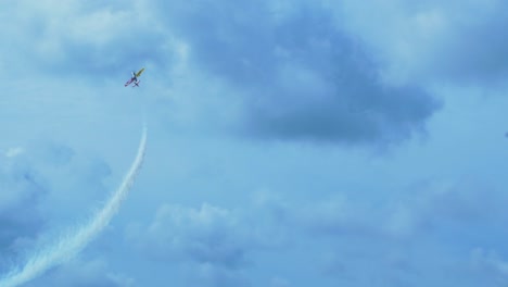 sukhoi su-26 aerobatic airplane carrying out dynamic maneuvers in front of spectators at baltic airshow in liepaja, latvia, white smoke trails, handheld tracking shot, 4k