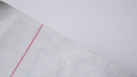 person takes off clamp from checkered paper sheets macro