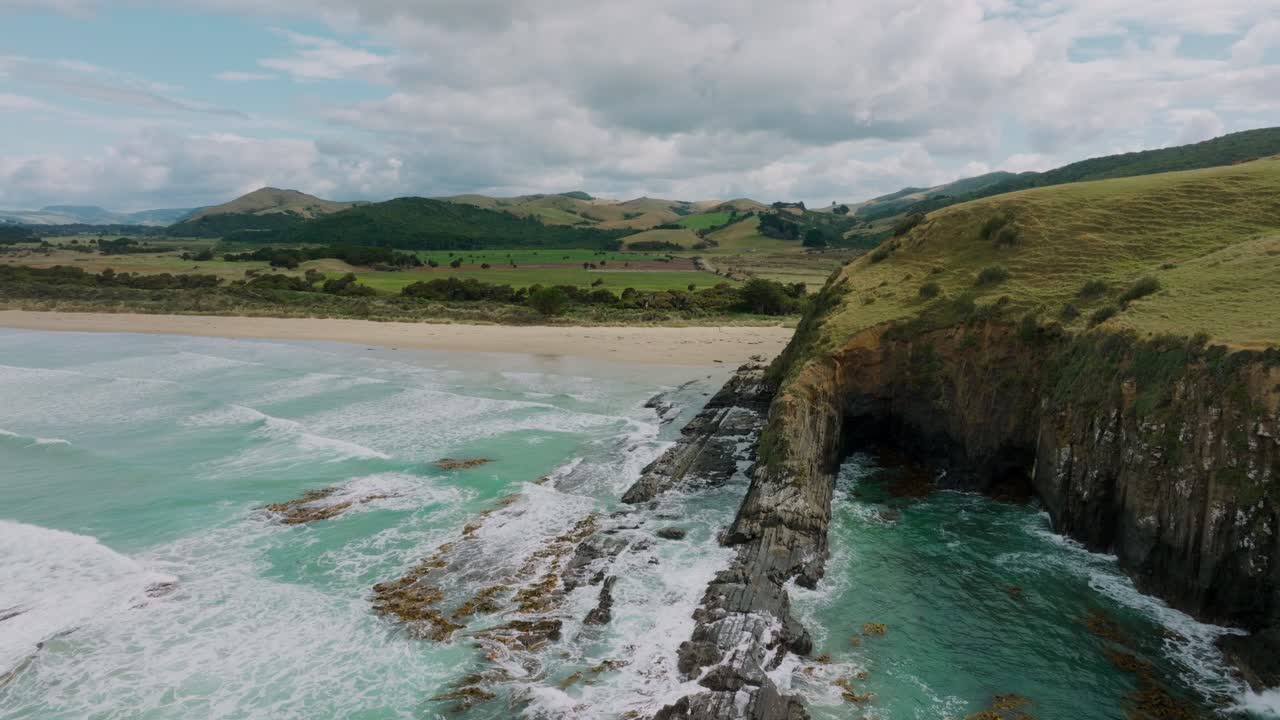 vista aérea de drones de olas blancas contra la salvaje, escarpada y empinada costa de la bahía de los caníbales en los catlins, isla sur de nueva zelanda aotearoa